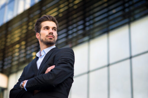 Young corporate businessman standing in front of an office building